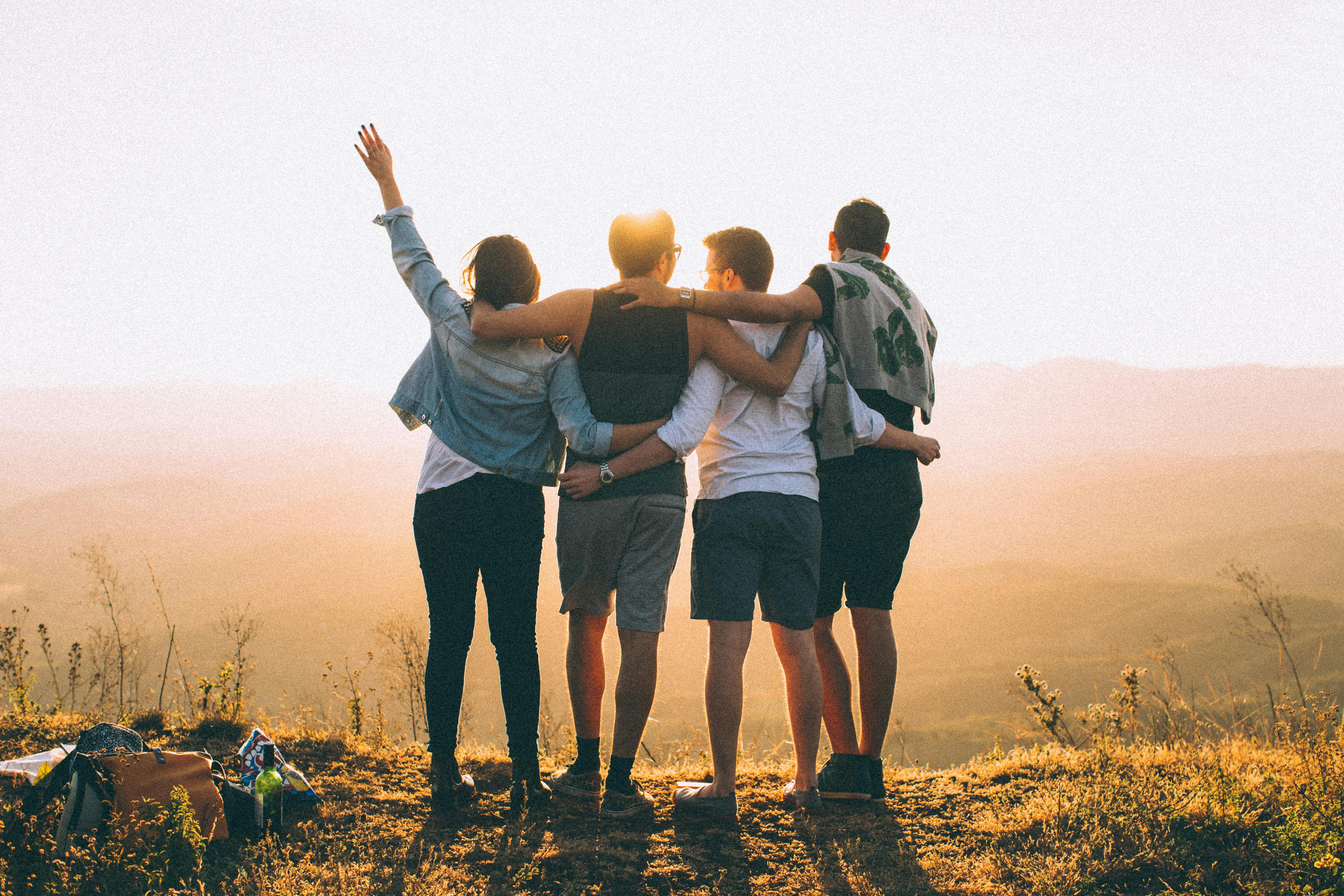 Four people with their arms around each other.