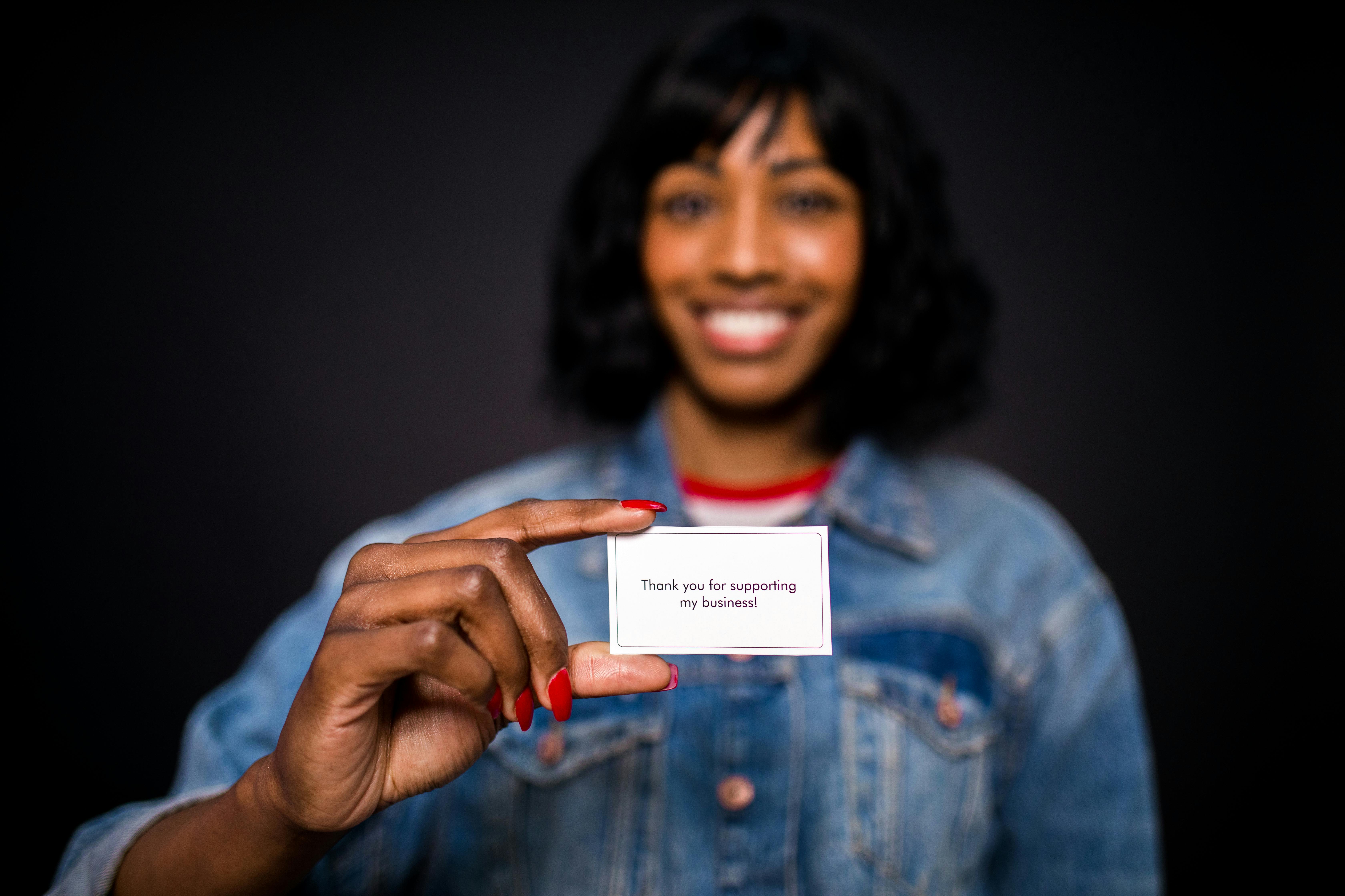 Woman holding a business card that says "Thank you for supporting my business!"