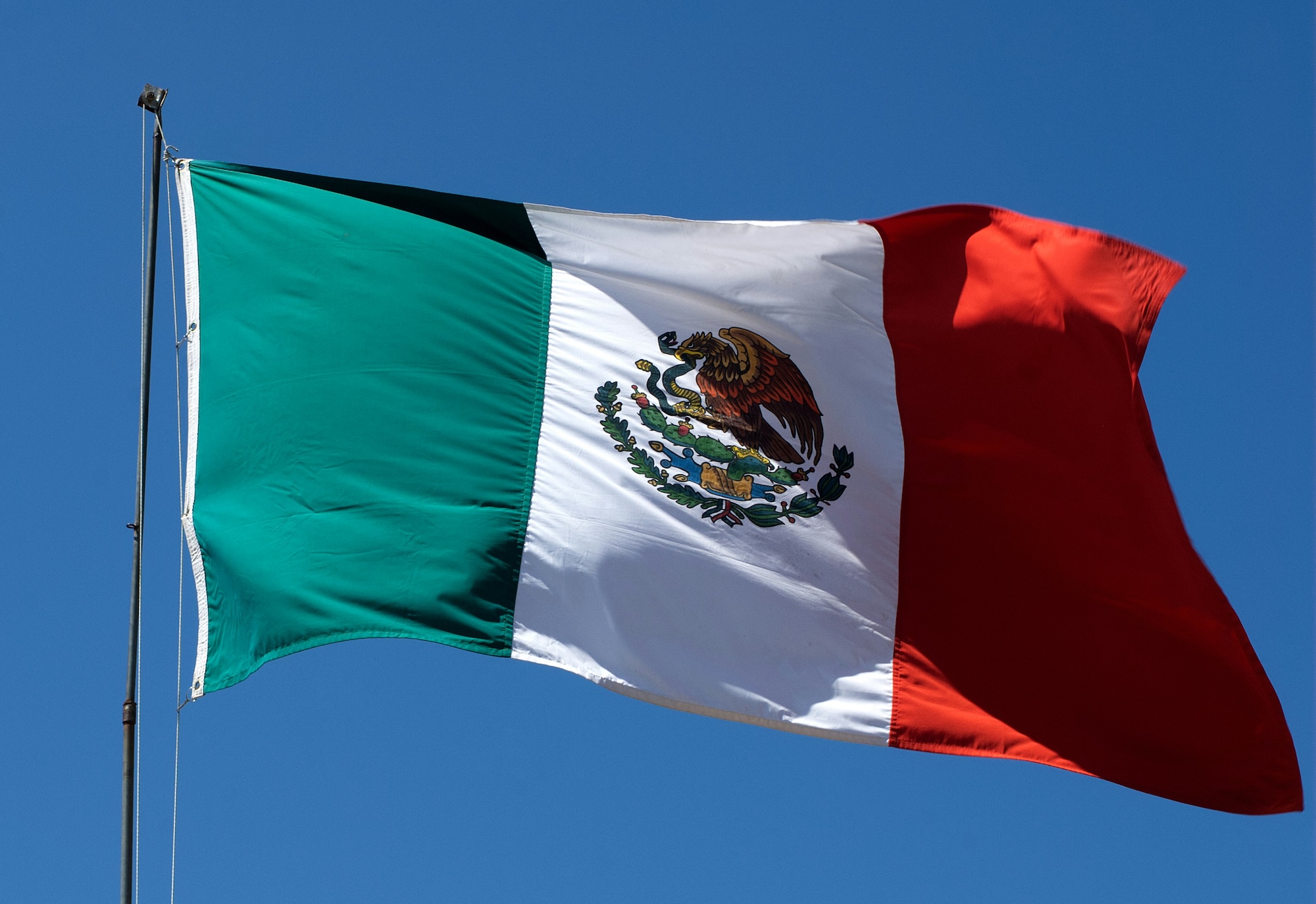 Mexico flag flying with blue sky behind it